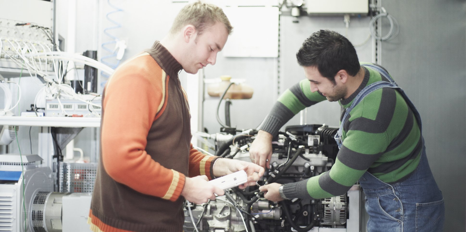 Two people working on one engine