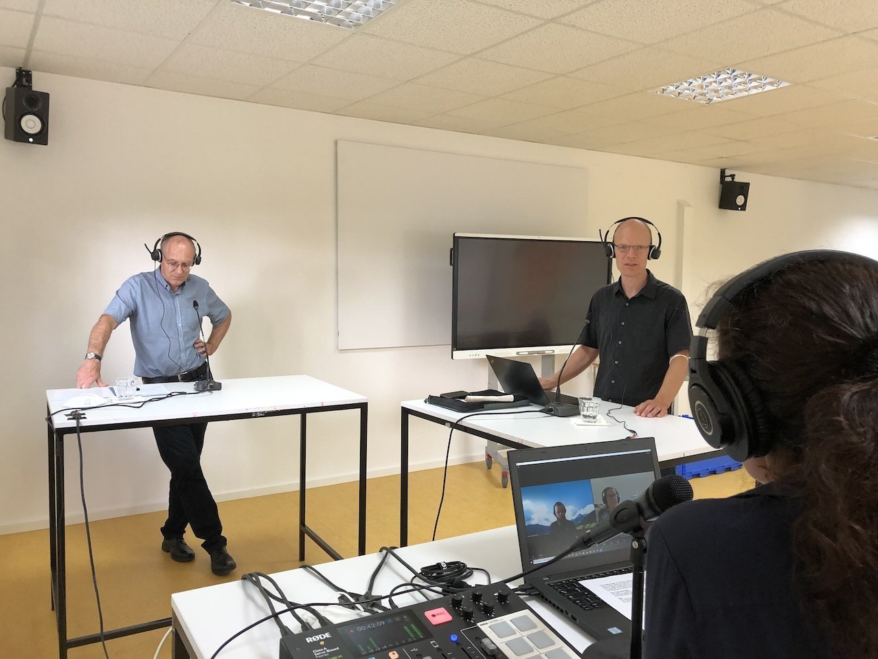 Die Gesprächsgäste an Stehtischen mit Mikrofonen im Podcastraum der h_da
