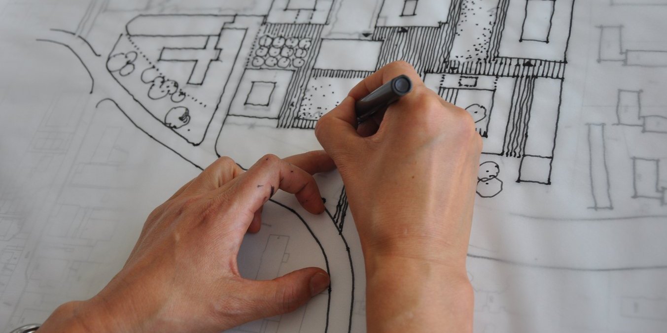 Hände mit Stift beim Zeichnen eines Architekturplanes